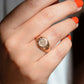 The ring is shown on the right ring finger of a Caucasian model in bright orangey-red nail polish.