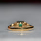 Close-cropped macro of a vintage ring, featuring a square emerald-cut emerald flanked by three round diamonds arranged in a triangular cluster on each shoulder. Viewed from the back to highlight the very good condition of the shank.